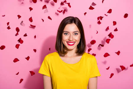 Photo of adorable sweet young woman wear yellow outfit roses petals falling smiling isolated pink color backgroundの写真素材