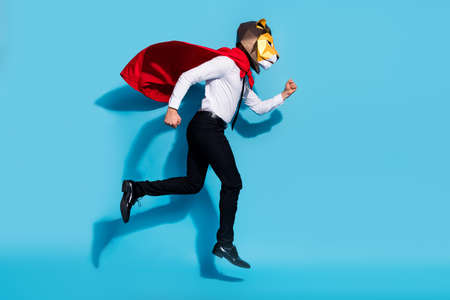 Full length profile side photo of weird guy lion mask wear red mantle jump up run hurry save world isolated over blue color backgroundの写真素材