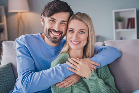 Photo of positive cheerful couple man embrace his sweetheart lady enjoy apartment room free time date relaxの写真素材