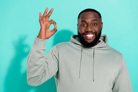 Portrait of attractive content cheerful guy showing ok-sign ad agree isolated over bright teal turquoise color backgroundの写真素材