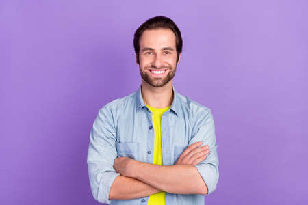 Portrait of smiling handsome businessman with folded arms successful freelancer isolated on violet...