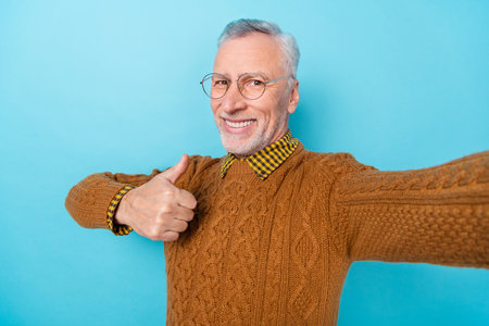 Photo of retired grandpa make shooting selfie thumb up great ad suggest isolated blue color backgroundの写真素材