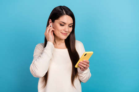 Photo of young charming woman use mobile tune headphones playlist song isolated over blue color...