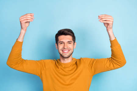Photo of pretty charming young guy dressed yellow pullover holding arms empty space smiling isolated...