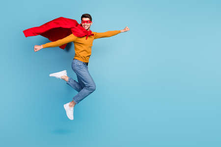 Full body profile side photo of young man happy positive smile fly air wear costume mask isolated over blue color backgroundの写真素材