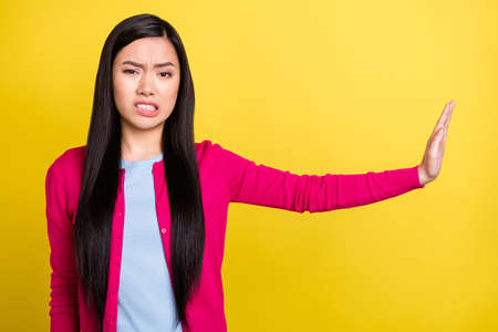 Photo of unhappy upset young woman hold hand empty space stop sign refuse isolated on yellow color...