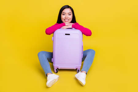 Full size photo of optomistic brunette young lady sit with bag wear pink sweater jeans isolated on yellow backgroundの写真素材