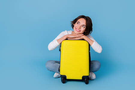 Photo of dreamy adorable lady dressed white shirt embracing baggage empty space isolated blue color backgroundの写真素材