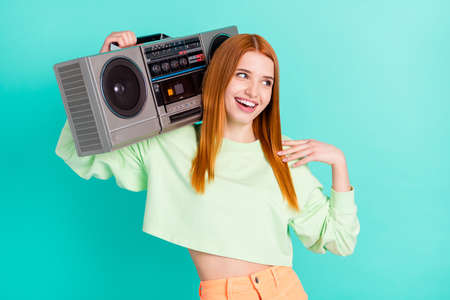 Photo of cheerful young happy lady look empty space hold shoulder boombox isolated on teal color...
