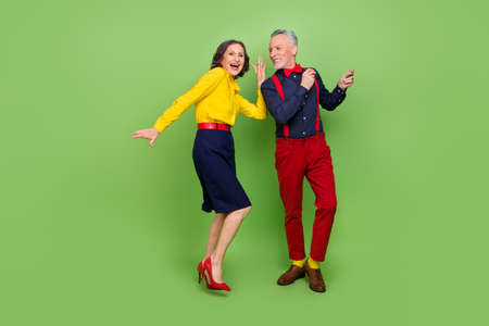 Full size portrait of two positive excited persons enjoy free time disco isolated on green color backgroundの写真素材