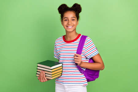 Portrait of attractive cheerful girl going back to school holding book library isolated over bright green color backgroundの写真素材