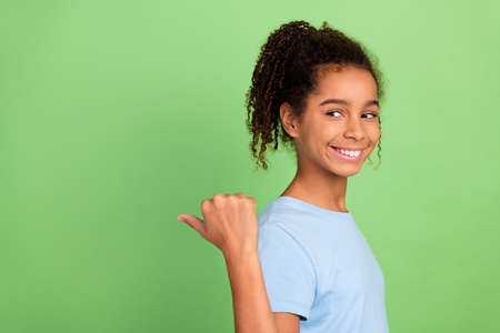 Portrait of attractive cheerful girl demonstrating copy space ad advert isolated over green pastel color backgroundの写真素材