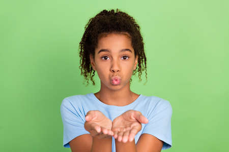 Photo of young afro multiethnic girl teenager plump lips send air kiss you romantic feelings isolated over green color backgroundの写真素材
