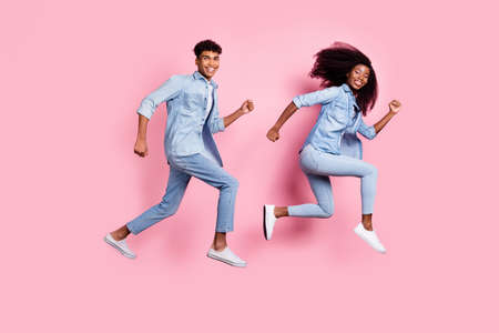 Full length body size view of beautiful cheerful friends friendship jumping running isolated on pink pastel color backgroundの写真素材