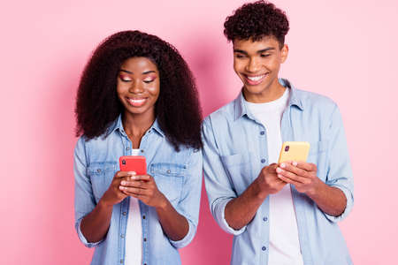 Photo of handsome guy look interested attractive dark skin lady phone isolated on pink color backgroundの写真素材
