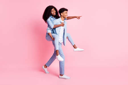 Full length body size view of beautiful handsome cheerful trendy friends friendship piggy backing showing way isolated on pink pastel color backgroundの写真素材
