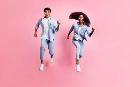 Full size portrait of two excited dark skin persons running open mouth smile isolated on pink color backgroundの写真素材