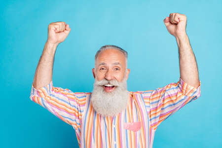 Photo of senior man happy positive smile celebrate victory hooray fan champion isolated over blue color backgroundの写真素材