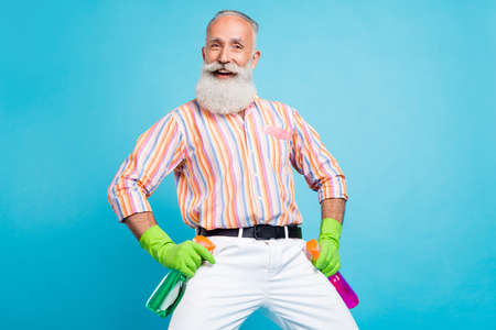 Photo of senior man happy positive smile cleaning household disinfection spray isolated over blue...