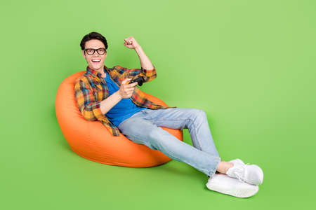Photo of astonished guy hold joystick celebrate victory wear eyewear plaid shirt isolated green...