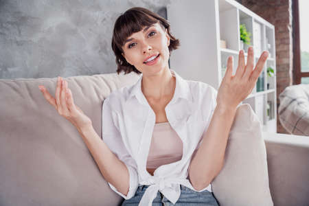 Photo portrait woman wearing white shirt talking on web camera staying at home sitting on couch