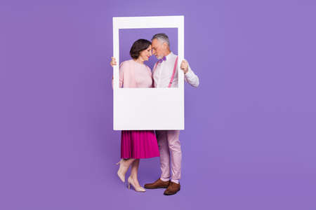 Full size portrait of aged elderly affectionate couple closed eyes touch head isolated on purple color backgroundの写真素材