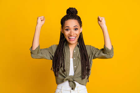 Photo portrait of excited woman cheering raising two fists up isolated on vivid yellow colored...