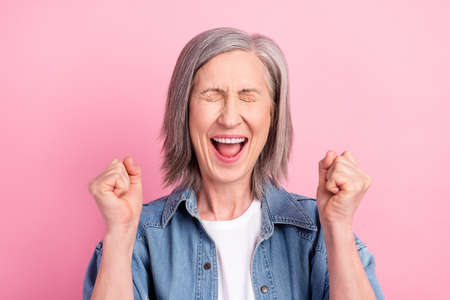 Photo of celebrate aged lady hands fists yell wear blue blazer isolated on pastel pink color backgroundの写真素材