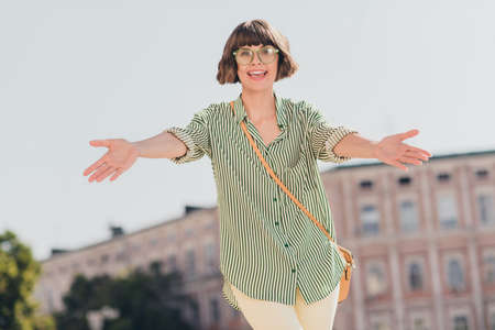 Photo of friendly inspired crazy lovely lady stretch hands invite cuddle wear specs bag striped shirt urban city outsideの写真素材