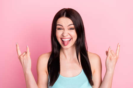Photo of young excited girl happy positive smile tongue-out show fingers rock sign isolated over...