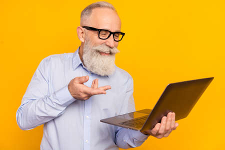 Photo of charming happy old businessman look laptop online meeting talk isolated on yellow color...