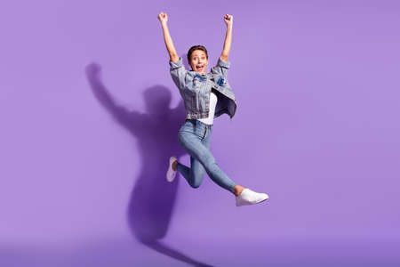 Full size photo of amazed shocked cheerful woman jump up raise hands celebrate isolated on violet...