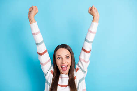 Photo of astonished funky lady raise hands triumphing wear striped sweater isolated blue color backgroundの写真素材