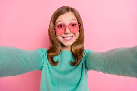 Photo of cheerful girl wear turquoise sweater heart glasses tacking selfie isolated pink color...