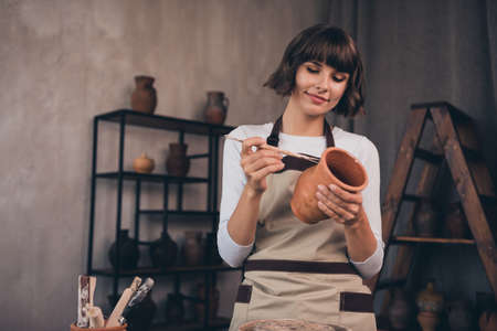 Photo of pottery owner lady potter doing client order carving decor crockery use equipment in...