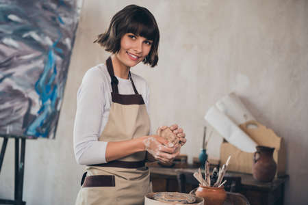 Photo of self employed professional lady potter seminar doing porcelain artwork earthenware pot in workroomの写真素材