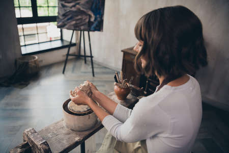 Back rear spine photo of pottery owner self-employed lady doing pot mud teach students artwork sit in workroomの写真素材