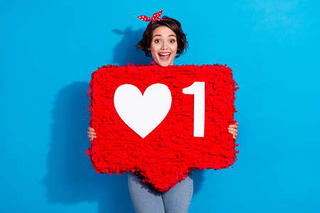Photo of young pretty woman hold paper pinata ads user button blogging isolated over blue color...