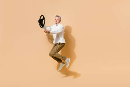 Full length body size view of attractive outraged man jumping holding steering wheel shout isolated...