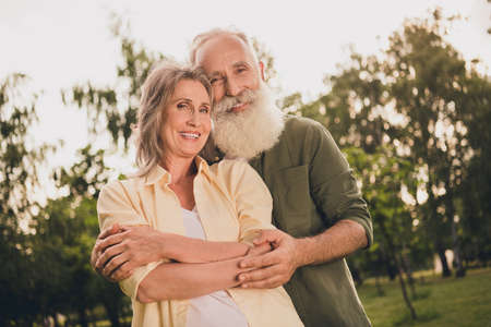 Photo of sweet old couple hug wear shirt walk in park outside outdoors