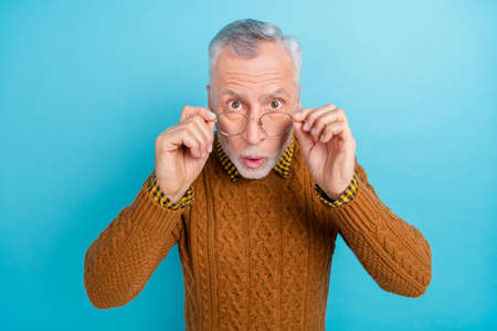 Photo of impressed funny man pensioner dressed brown pullover arm glasses big eyes isolated blue...