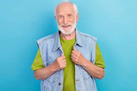 Photo of pretty handsome retired man wear vintage jeans waistcoat smiling isolated blue color...