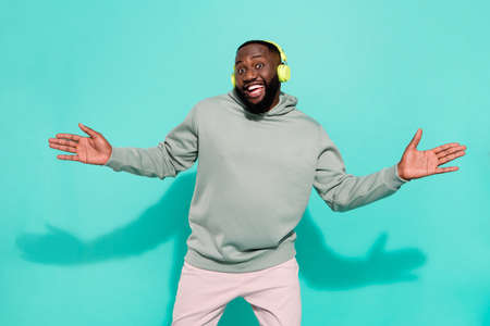 Portrait of cheerful attractive guy dancing listening pop hit single isolated over vibrant teal turquoise color backgroundの写真素材