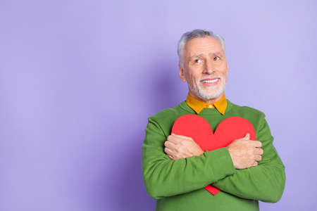 Photo of charming man pensioner dressed green pullover hugging big heart empty space isolated purple color backgroundの写真素材