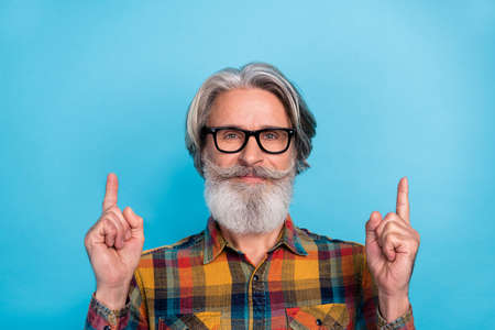 Photo of senior man indicate fingers empty space promoter decision banner advert isolated over blue...