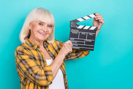Photo of senior woman shooting movie cinematography hold clap board isolated over teal color background.の写真素材