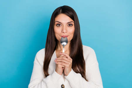 Photo of cool mature lady lick spoon wear white sweater isolated on blue color backgroundの写真素材
