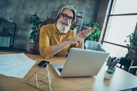 Photo of clever busy senior man wear yellow shirt glasses video chat modern device indoors workshop workplaceの写真素材