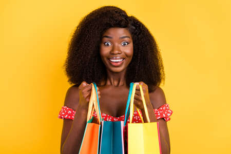 Portrait of gorgeous cheerful girl black friday bargain hold bags full of clothes shopaholic isolated on yellow color backgroundの写真素材