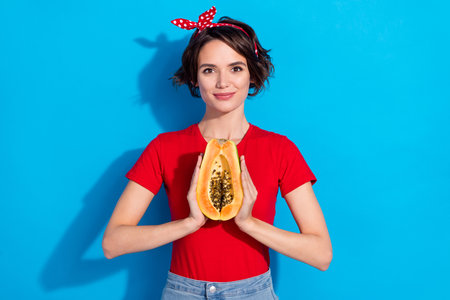 Photo of young pretty woman hold half papaya organic fresh tasty bio grocery isolated over blue color backgroundの写真素材